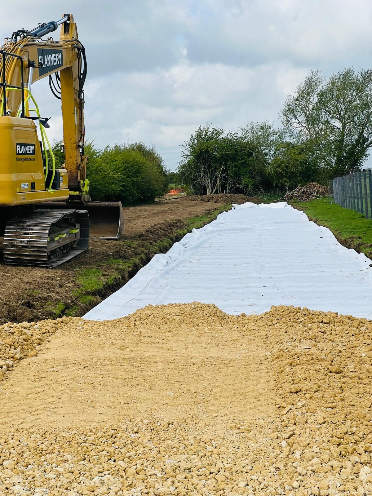 Geotextile membrane laid over the formation with crushed stone being placed over it to build an access road at a 24MW solar site in Cambridgeshire.