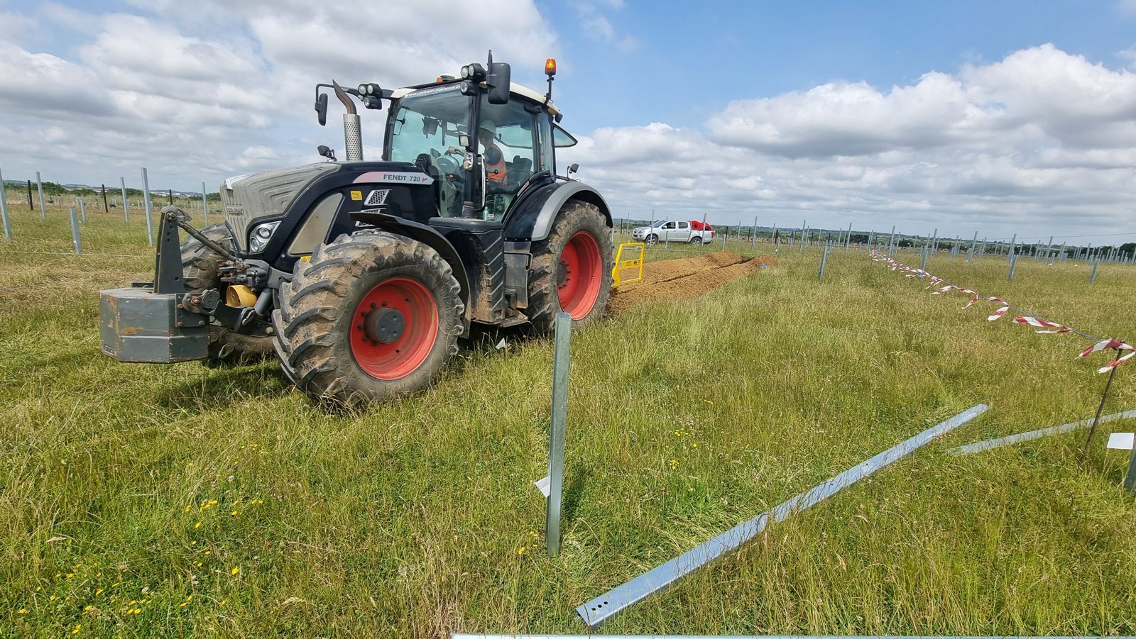A tractor plough-trenching cable across a field.