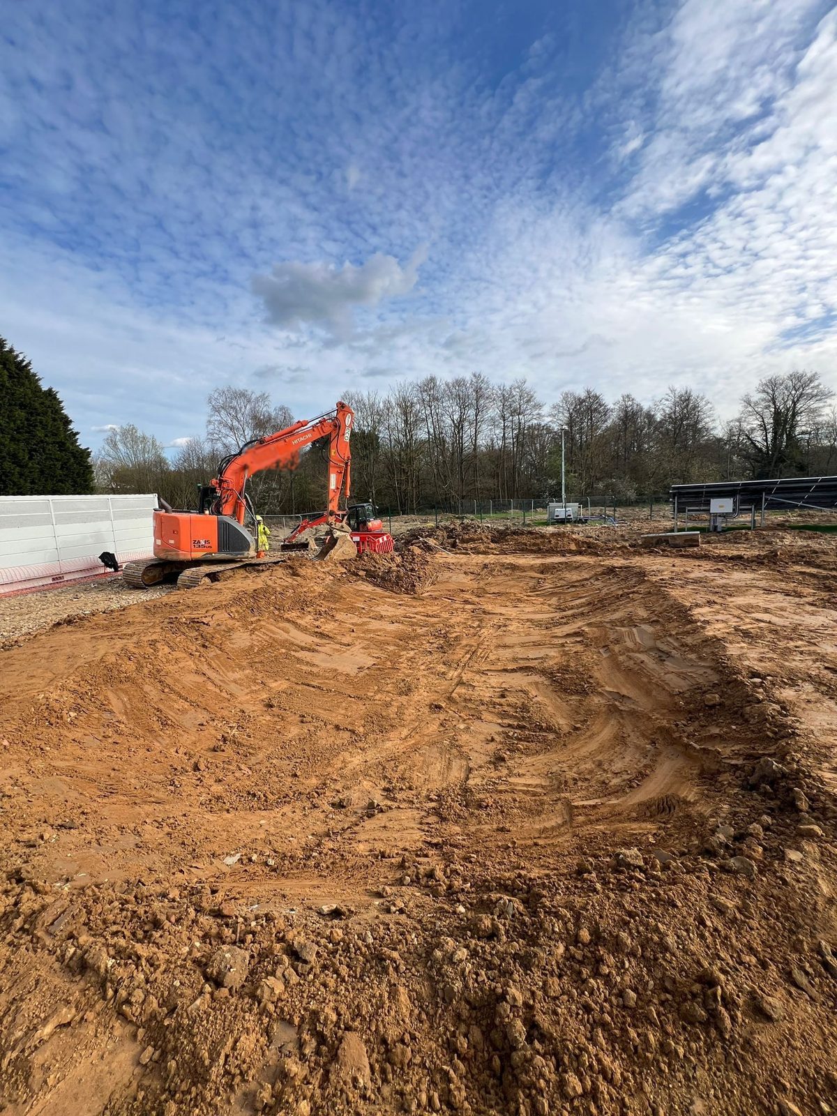 Excavator shaping a balancing pond at a BESS and solar site in East Sussex.