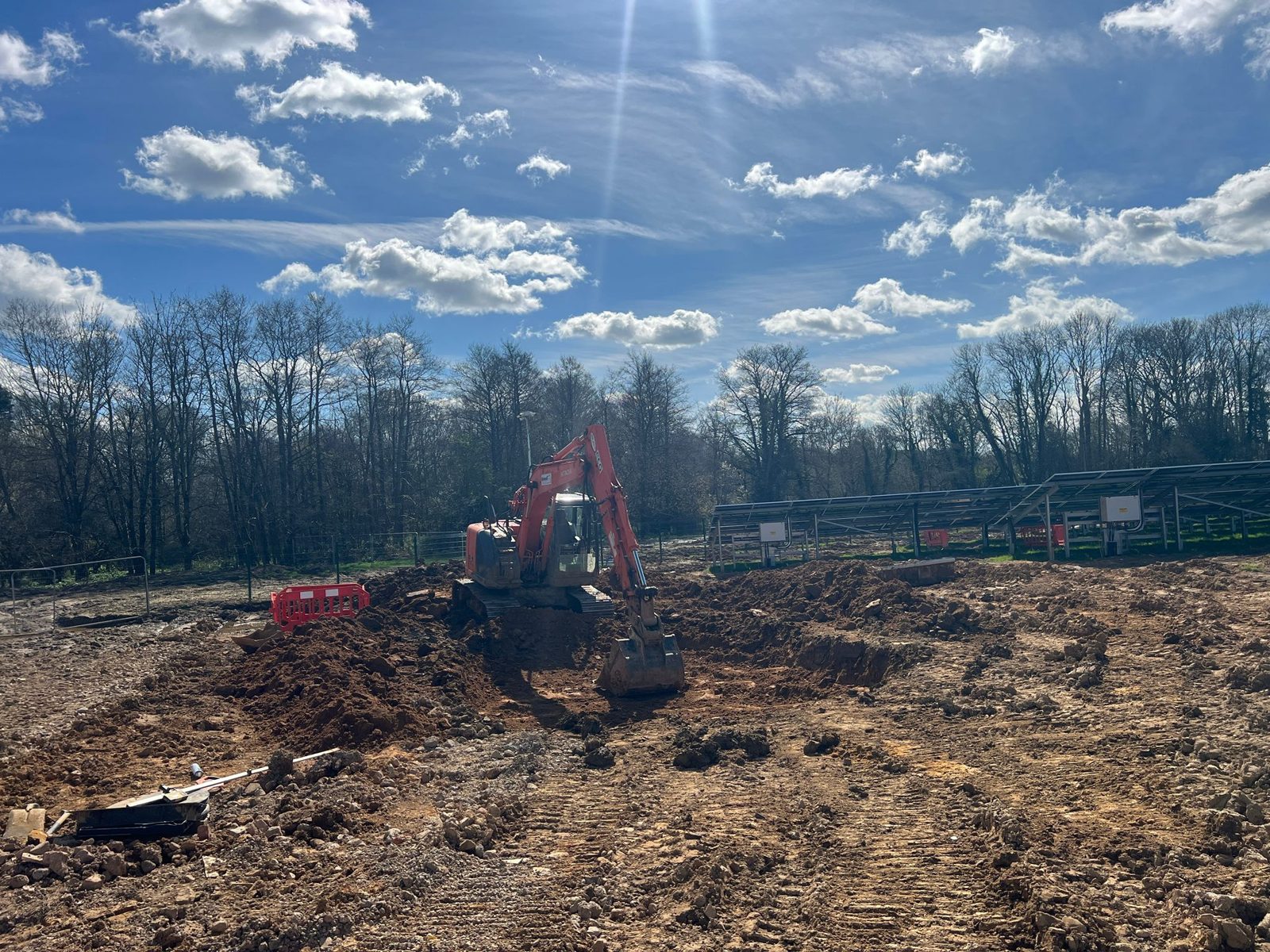 An excavator shaping a balancing pond at a BESS and solar site in East Sussex.