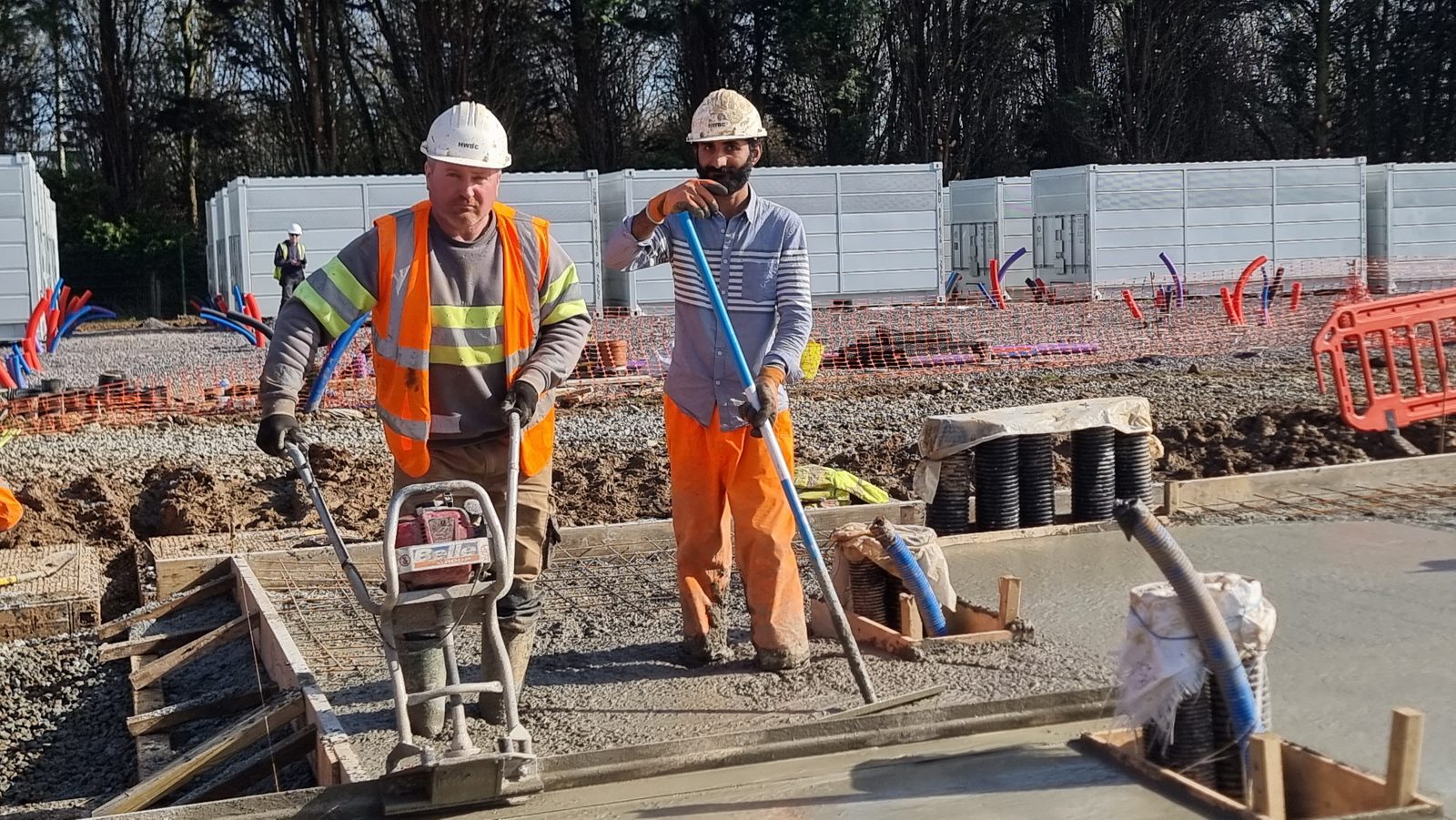 Two HWBC operatives finishing a concrete base pour at a BESS and solar site in East Sussex.