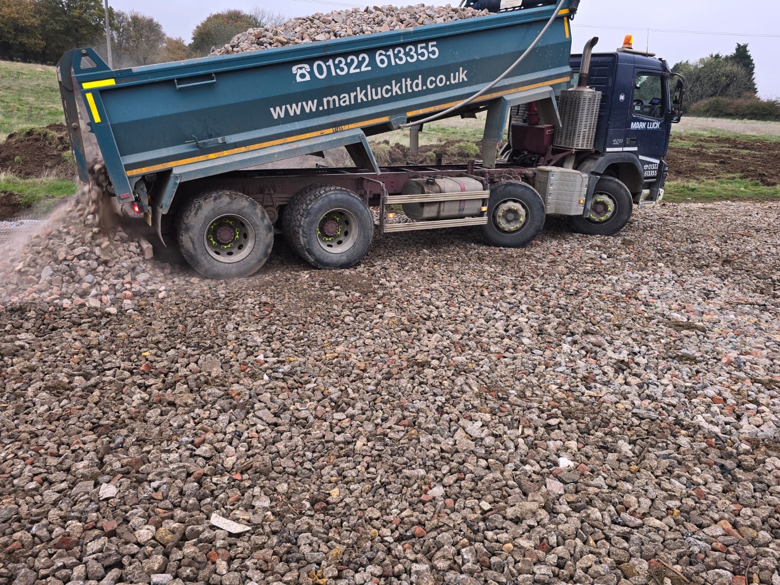 A tipper delivering crushed stone to build up an access road.