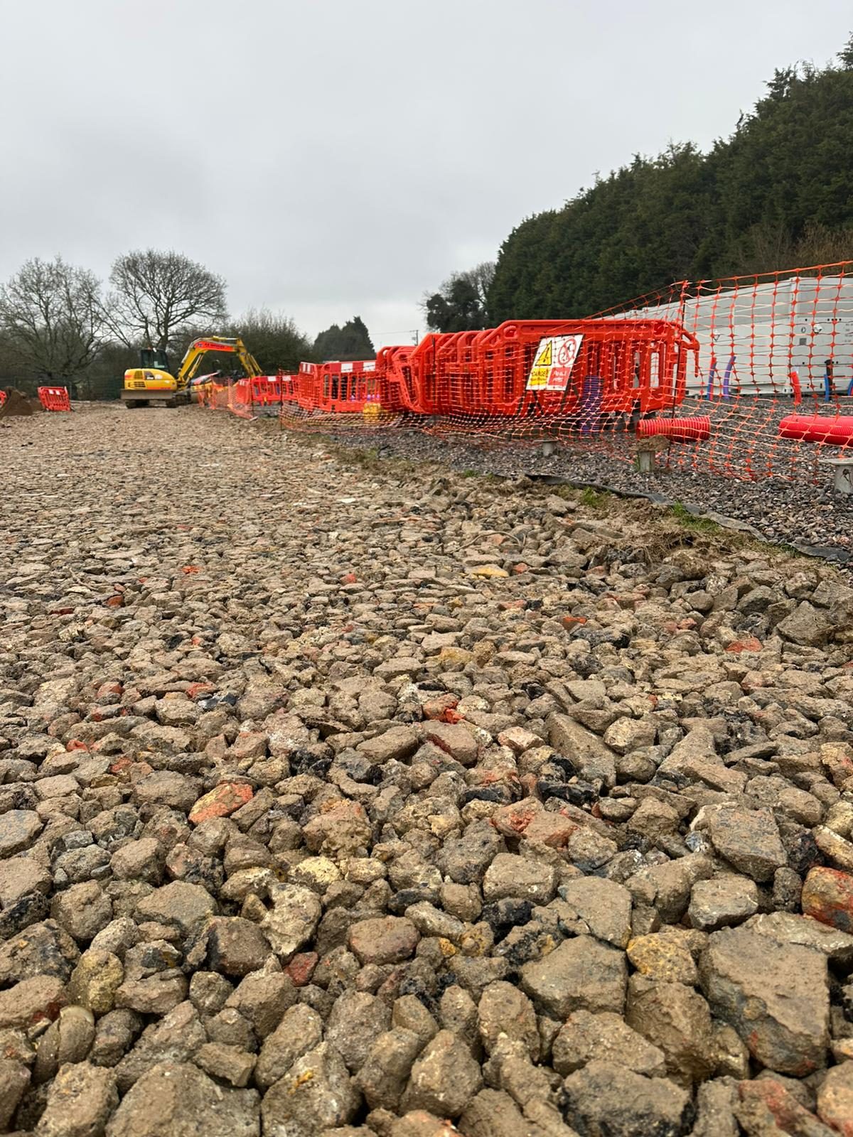 A finished crushed-stone access road and compound surface at a BESS and solar site in East Sussex.