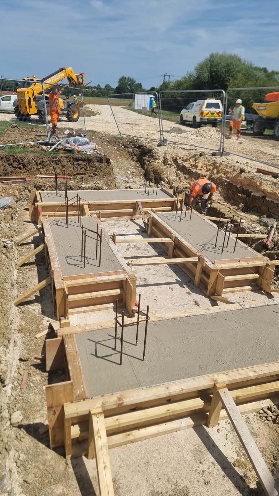Freshly poured reinforced concrete bases with projecting starter bars and timber formwork in Cambridgeshire.