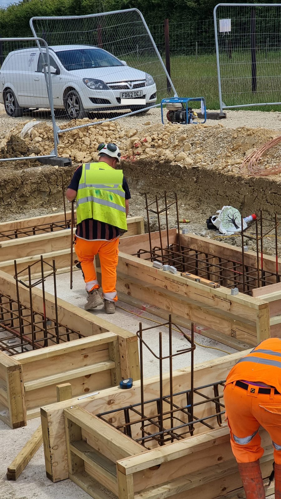 Steel rebar cages set in timber shuttering for reinforced concrete foundations in Cambridgeshire.