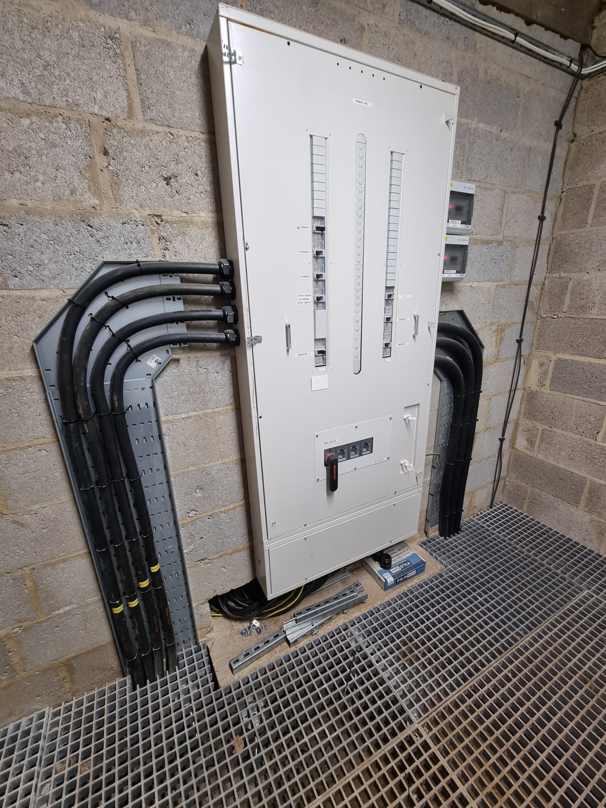 An AC distribution board with armoured cabling on cable tray inside an HWBC-built control room with a GRP grating floor.