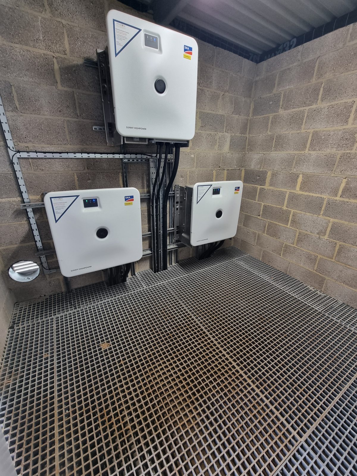 Three SMA Sunny Highpower inverters wall-mounted on unistrut inside a self-contained control room built by HWBC, with a specialist GRP grating floor.