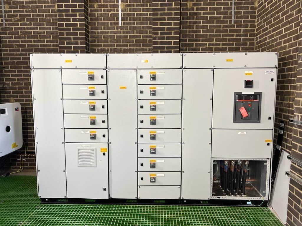 A floor-standing LV switchgear and distribution lineup inside an HWBC-built control room with a GRP grating floor.